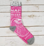 Image shows the pink socks with a white drawing of a sloth resting on a wooden table.