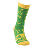 This green sock with a yellow top, heel, and toe sports a design of different items, such as a camper, a fishing hook, a boat, and the sun. A yellow square sits at the bottom with the words, "Adventure Awaits" in green lettering.