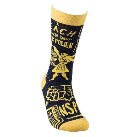 This black sock with a yellow top, heel, and toe has a picture of a female superhero and a picture of the United States. Above and below the images are the words, "I Teach What's Your Superpower Inspire" in yellow lettering.