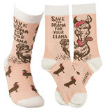 This picture shows the socks from both sides. On the one side are the brown llamas wearing the hats and the words, "Save the Drama for Your Llama" at the top. On the other side is a large brown picture of a llama wearing the red scarf and red hat.