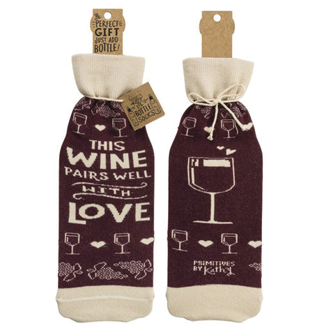 The "Pairs Well" bottle cover has text that reads "This Wine Pairs Well With Love" in white text over a purple background on the front and an illustration of a wine glass over a purple background on the back. 