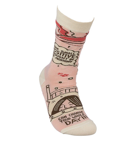 The "Positive Thoughts" sock is pink and white with red and brown line art of a woman's face under the bed covers and words that say, "One Small Positive Thought in the Morning can Change you whole Day". 