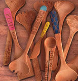 The spoon with the words, "Flip Out" is shown mixed with other spoons lying on a wooden table.