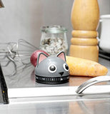 A Cat shape kitchen timer on a counter with a yam and a onion in the background.