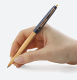 A person's hand is shown writing with the blue and copper pen.
