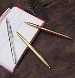 The three different-colored pens are shown lying on a table with an open notebook.
