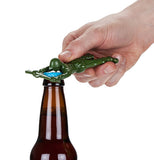 A hand holding a Green Soldier bottle opener on the cap of a brown glass bottle