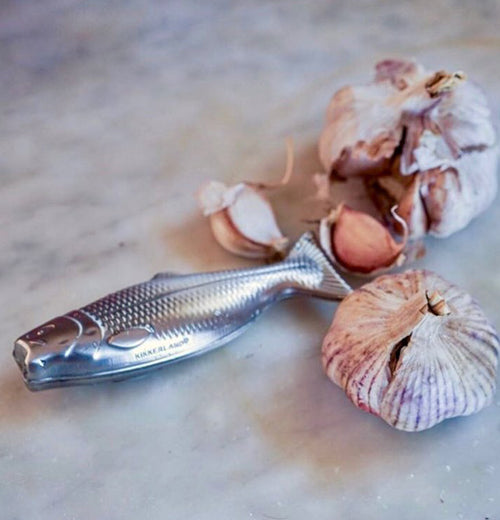 The Magic Soap "Fish" sits on a wooden table with two cloves of garlic. 