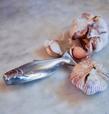 The Magic Soap "Fish" sits on a wooden table with two cloves of garlic. 