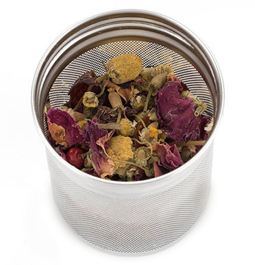Silver colored stainless steel infuser filled with loose leaf tea leaves on a white background.