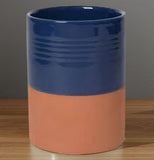 Navy blue glazed and brownish-red terracotta kitchen utensil crock on wood.
