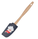 This rubber spatula with a black head and wooden handle has a picture of a Santa Claus head with his red hat in a curved position. The spatula is also shown in a diagonal position.