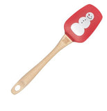 This rubber spatula with a red head and wooden handle has a picture of a snowman with a carrot nose.