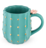 The green mug with the pink flower and golden spots is shown from a slightly different angle.
