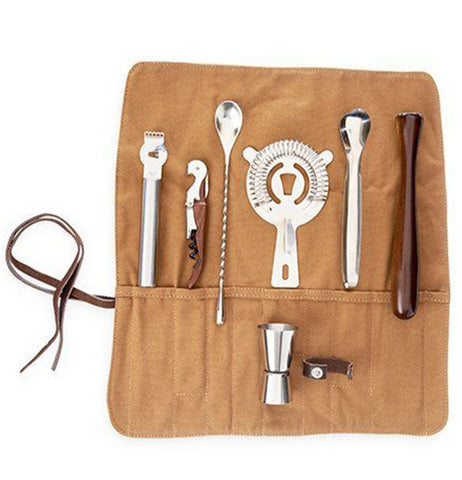 The cocktail kit which includes: a spoon, corkscrew, and jigger, are shown in an unrolled canvas pouch.