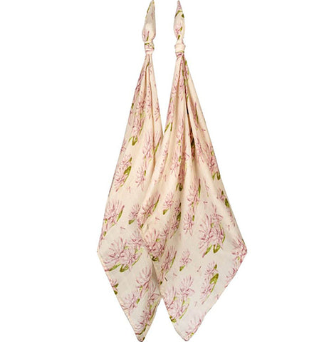 A pastel pink muslin burp cloth with slightly darker pink waterlily flowers with green leaves underneath.