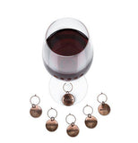 The charm that says, "Gather" is shown attached to a wine glass filled with red wine while the others are all sitting in front of the glass.
