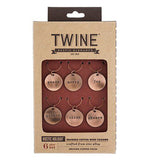 The six charms are shown inside their cardboard packaging. The word, "Twine" is shown at the top in black lettering.