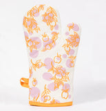 This is a picture of and orange and white oven mitt with a pattern of apples on tree branches.