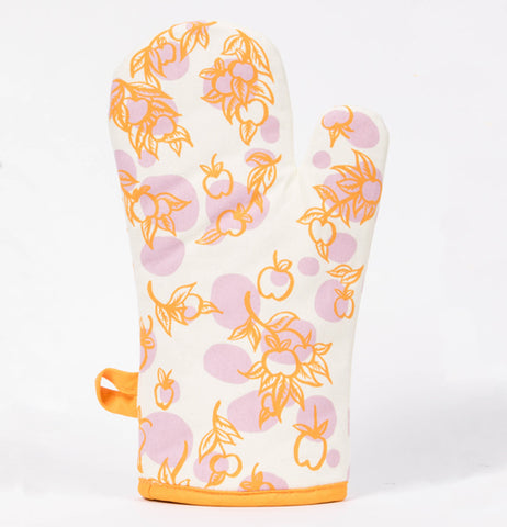This is a picture of and orange and white oven mitt with a pattern of apples on tree branches.