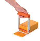 The slicer cuts through the cheese with the roller keeping the slice flat and even
