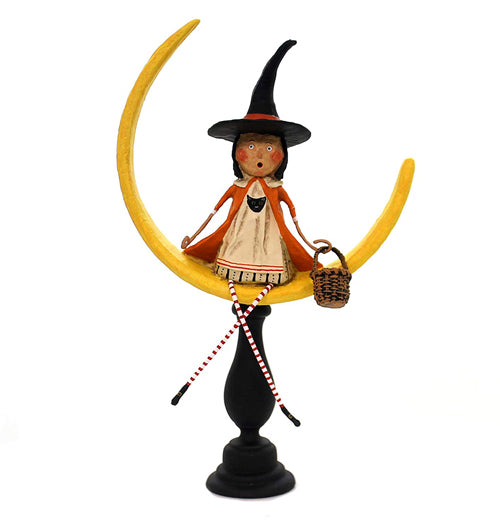The "Moonlight Magic" has a woman figurine sitting on a yellow crescent moon wearing a white dress and a orange cape with a black witch&