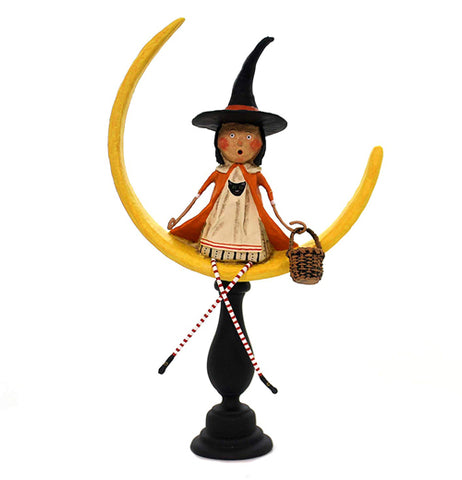 The "Moonlight Magic" has a woman figurine sitting on a yellow crescent moon wearing a white dress and a orange cape with a black witch's hat. 