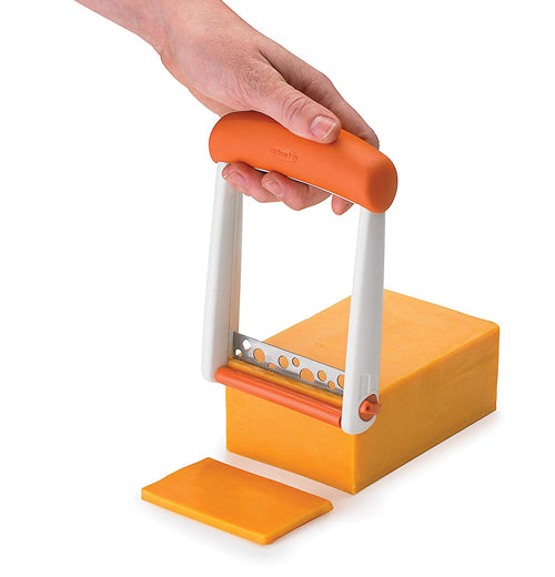 Holding the steel slicer, about to cut a slice from the cheese