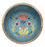 This wooden bowl has a blue bottom interior with a design of two bees pollinating a red flower. Two yellow flowers stand on either side of the red flower.