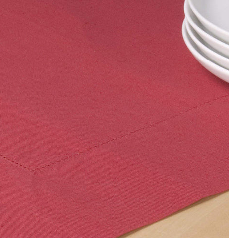 This chili Hemstitch tablecloth is on a table with some plates.