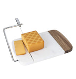 This white and brown cutting board has a long wire cutter attached to a steel handle. Some cheese is shown being sliced by the wire cutter.