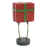 A polyresin figure of a child in a red, green, and white polka dotted wrapping present costume. The photo is from the back, and has no background.