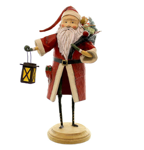 This old time Santa Claus figurine is wearing a red and white coat with a toy and a tree on his back and is carrying a lantern.