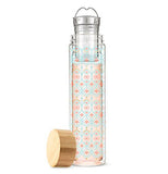 The thin glass mug with the turquoise criss-cross pattern around the red cross shapes is shown with its metal infuser and wooden lid.