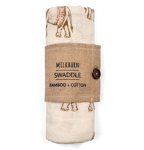 The white blanket with the gray elephants wearing brown tutus is shown wrapped up in its bamboo wrapping with the logo, "Milkbarn" in its middle.