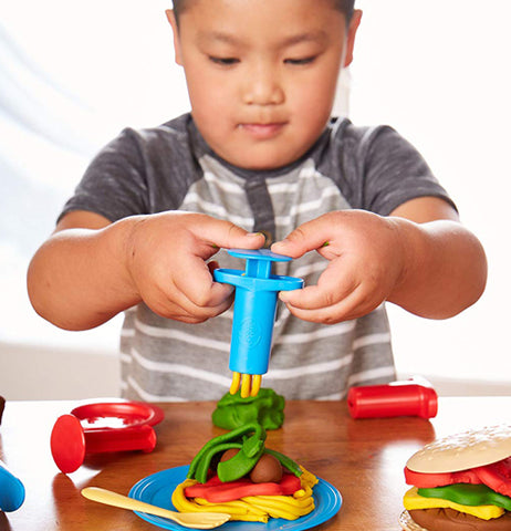 A boy using a dough tube for the hamburger from the Meal Maker Dough Set.