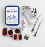The bicycle repair kit lies next to the items in the kit such as patches, wrenches, buffer, metal tire levers, glue, and an Allen wrench set.