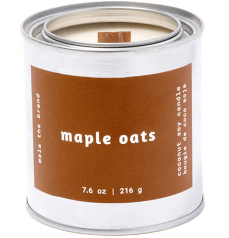 A gray tin candle-shaped can with a brown label. The label says "Mala the brand--maple oats--Net weight 7.6 oz. -- coconut soy candle."