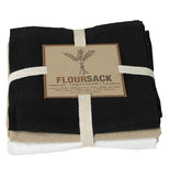 This set of three different tea towels all tied together have a sign with a picture of a wheat plant with the word, "Floursack" beneath it in brown lettering. The towel at the bottom is white, the one in the middle is tan, and the top one is black.