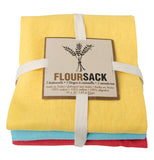 Set of 3 floursack dish towels one lemon yellow, one turquoise, and one grenadine red wrapped in white twine with label that reads FlourSack on a white background.