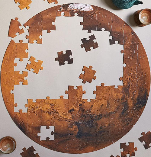 A round, circular puzzle of Mars is in the process of being completed.