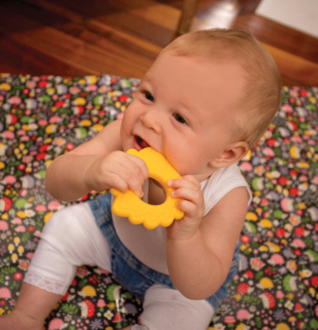 A baby seeking his teeth on the yellow Silicone "Hedgehog" Teether.