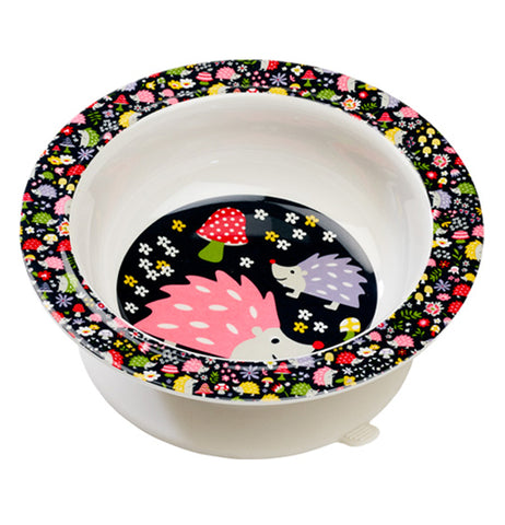 This white bowl with a black rim and bottom features a design of yellow, red, periwinkle, and green flowers on its rim, and a pink and periwinkle hedgehog pair on the bottom standing in front of a red and green mushroom.