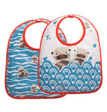 This image shows two bibs with two different designs, both with red outline around the bibs. One bib has a design of waves of blue water with baby otters scattered around. The second one has a design of blue water that fills the bottom half of the bib and the top half shows two otters with their bodies inside the water, but with their heads sticking out of the water.