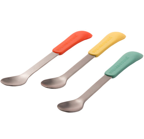 A set of three steel spoons are shown with different colored silicone handles. The first handle is orange, the second is yellow, and the third is teal green.