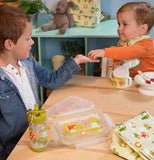 A young boy and baby are shown sitting at a wooden table with the alligator bottle in front of them.