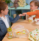Two boys are shown sitting at a wooden table; to their right sits the lunch sack covered in the alligator design.