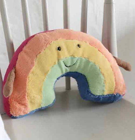 "Amuseable Rainbow" stuffed toy with pastel peach, yellow, and turquoise stripes and tan arms sitting in a white wooden chair.