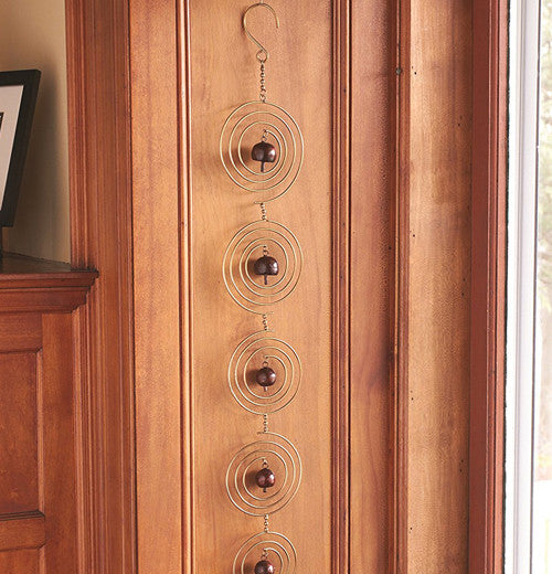 Spiral bell chain hanging on wood colored wall.