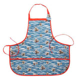 This blue and white apron, outlined in red, features a design of brown baby sea otters floating on the water's surface.